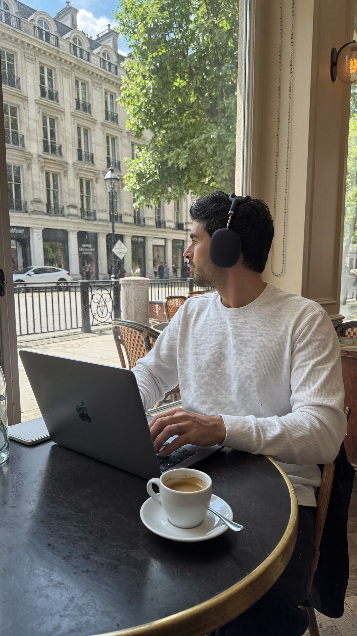 DTC operator working from a cafe with a laptop and phone, running an AI-powered business remotely